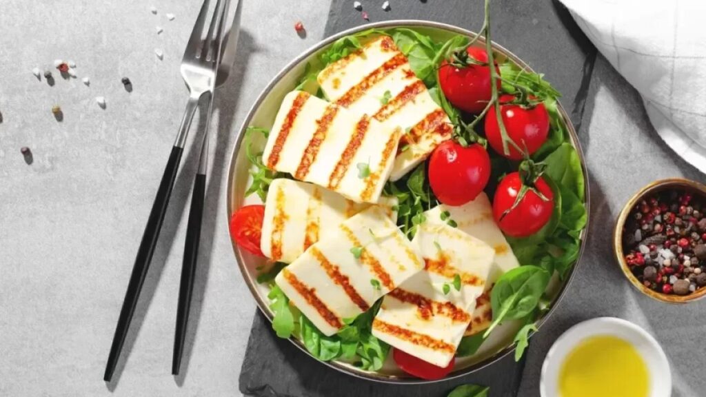 Grilovaný halloumi se zlatavou kůrčičkou na talíři s čerstvou zeleninou