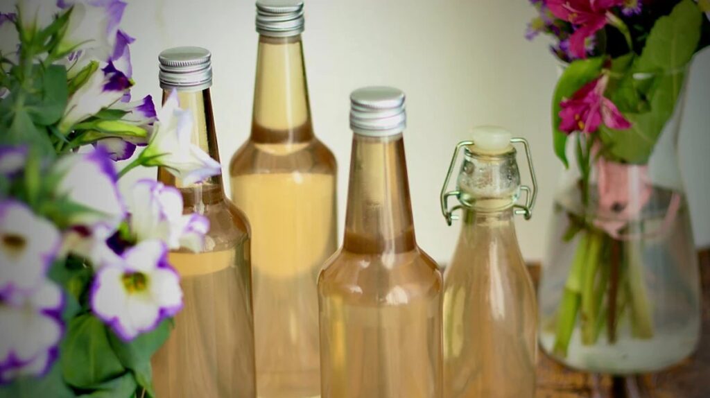 Domácí kopřivový sirup ve sklenici vedle čerstvých kopřiv